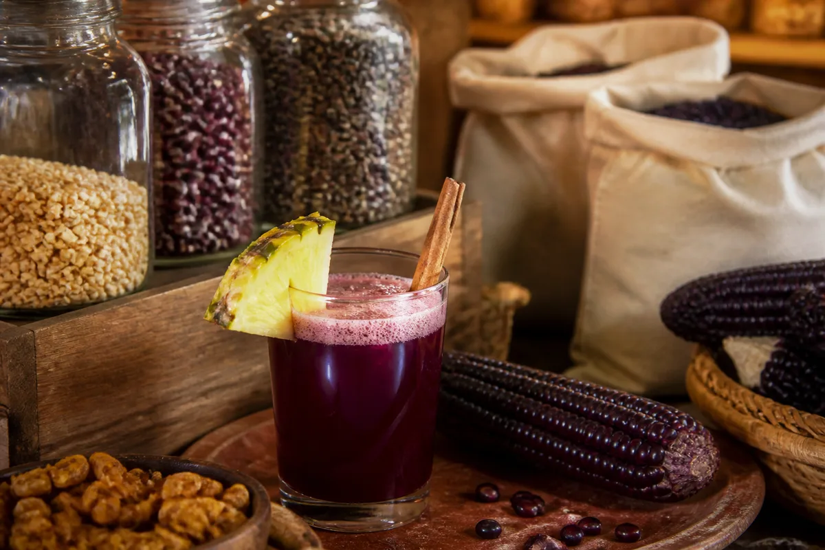 Verre de boisson au maïs violet garni d&rsquo;une tranche d&rsquo;ananas et d&rsquo;un bâton de cannelle